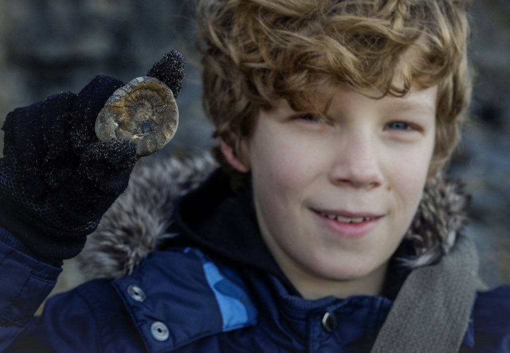 Smiling boy with an ammonite fossil - Yorkshire Coast rocks
