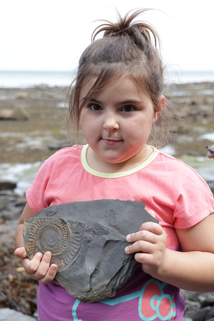 girls holds a fossil she found